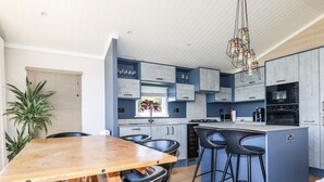Una cocina moderna con una mesa de comedor de madera, taburetes negros tipo barra y una isla integrada.