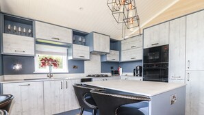 Una cocina moderna con una isla central, taburetes de bar y electrodomésticos integrados.