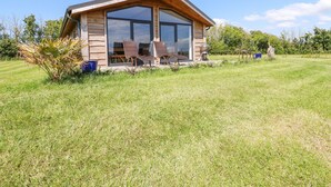 Una casa moderna con un gran ventanal, fachada de madera y un césped.