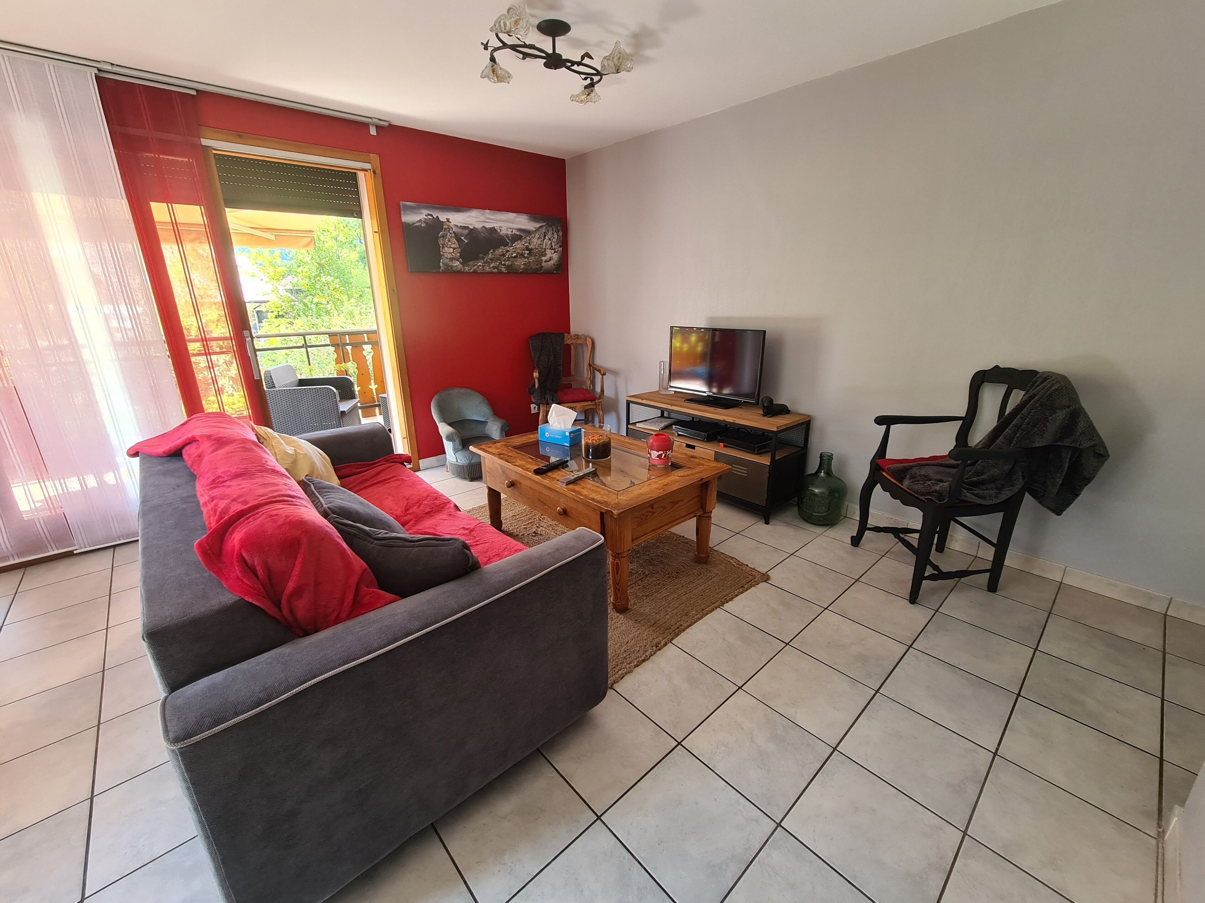 Una sala de estar con un sofá, una mesa de centro, un televisor y una silla.