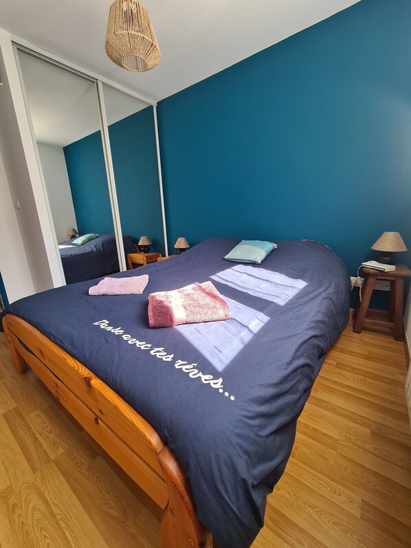 Ein Schlafzimmer mit einem Bett, Holzboden und einem Spiegel.