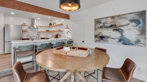 A modern kitchen with white cabinetry, a central island, and a dining area with a round table and leather chairs. - CDA ID. Sanders Beach! Best Location! Newly Remodeled Addition! Pet Friendly. (Coeur d'Alene)