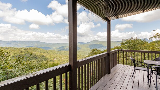 A wooden deck with a table and chairs, overlooking a mountainous landscape. - Beautiful Sugar Mountain Condo with Long-Range Views (Sugar Mountain)