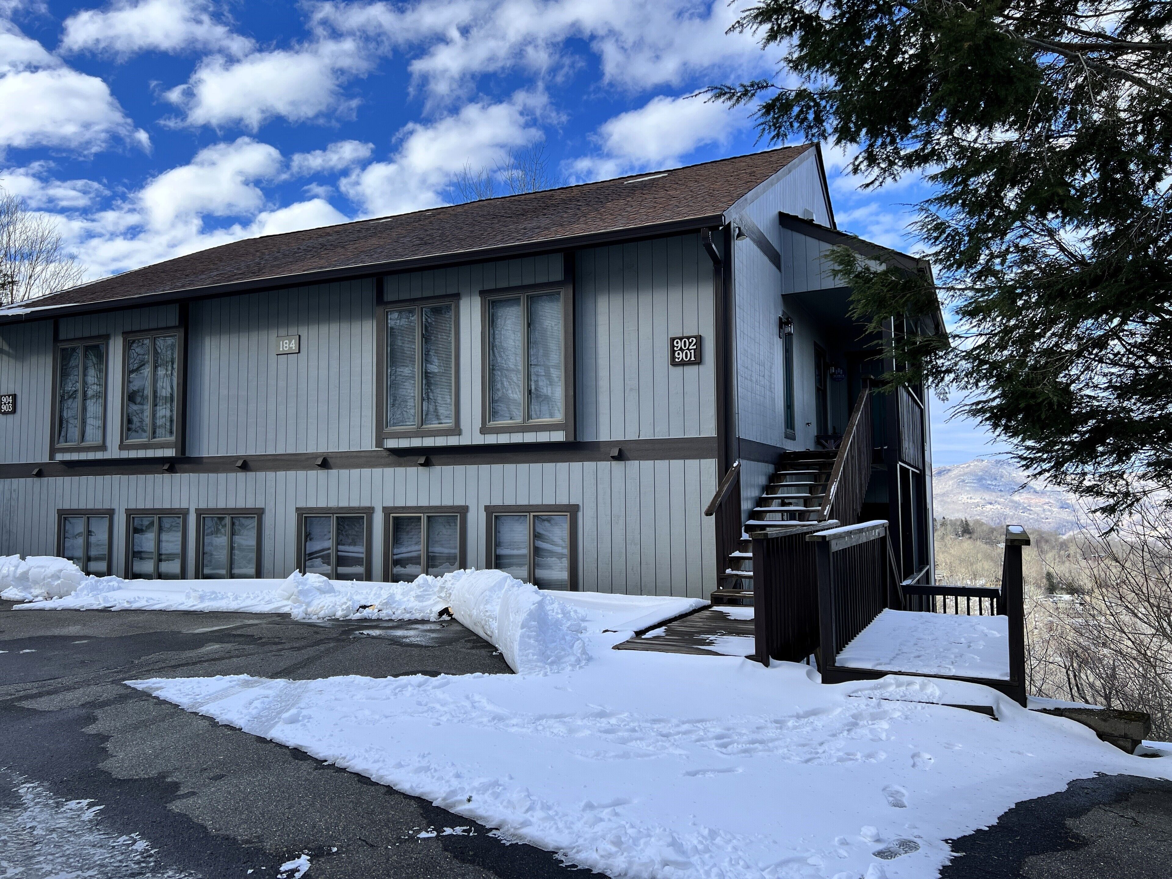 A two-story building with a staircase leading to the entrance, surrounded by snow.