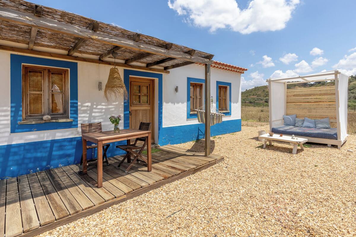 Ein Haus mit einer Holzdiele, einem überdachten Sitzbereich und einem Kiesgrundstück.