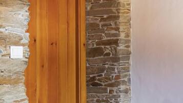 A wooden door with a stone wall and a white wall adjacent to it.