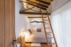 A bedroom with a loft bed, a wooden ladder, a bedside table with a lamp, and a white headboard. - Casas de Campo do Castro da Cola (Ourique)