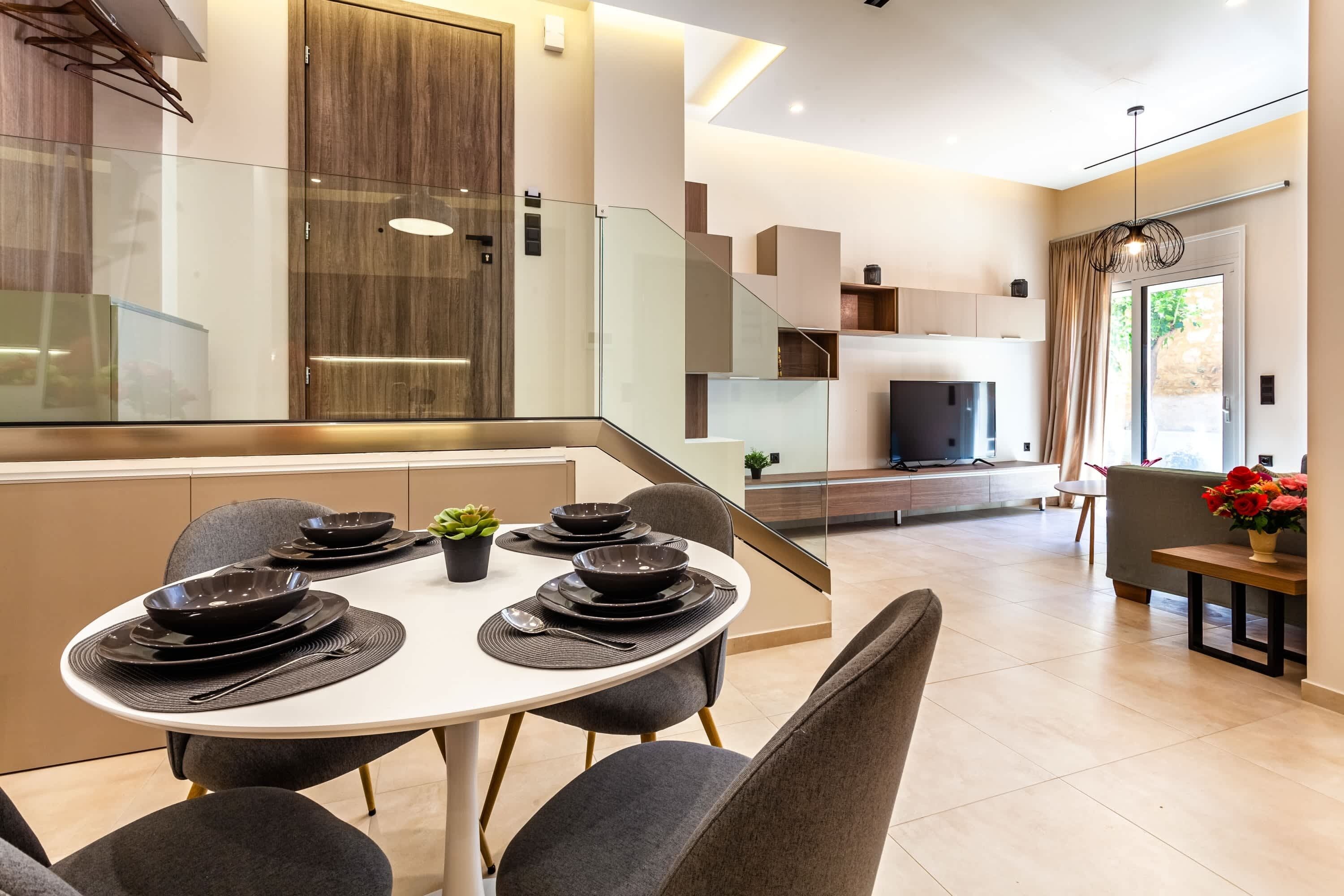 A modern kitchen with a dining area, a staircase, and a living room with a fireplace.