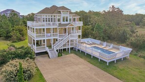 A multi-story house with a large deck and a swimming pool.