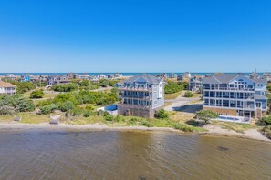 A coastal residential area with multiple two-story houses featuring balconies and large windows, likely offering ocean views. - Soundfront Home w/ Pool, Hot Tub, Elevator, Theater. Private Windsurfing Access (Rodanthe)