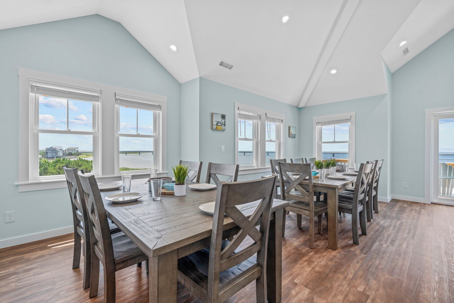 A spacious dining area with a high ceiling and large windows offering a view of the sea.