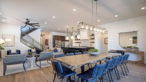 Une cuisine moderne dotée d’un grand îlot central, d’appareils électroménagers intégrés et de luminaires suspendus.