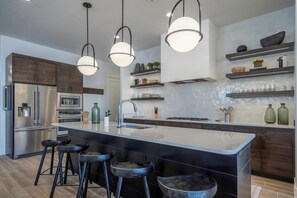 A modern kitchen with a large island, stainless steel appliances, and bar stools.