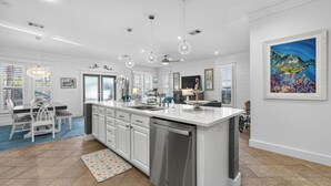 A spacious kitchen with white cabinetry, a stainless steel dishwasher, and a large island. - Updated Kitchen & Large Pool– Seacrest Simplicity Meets Coastal Comfort (Inlet Beach)