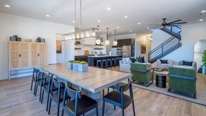 Une cuisine spacieuse avec un coin repas, un escalier et un salon doté de fauteuils verts.