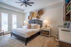 A bedroom with a bed, bedside tables, a ceiling fan, and wall decorations.