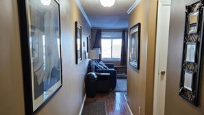 A hallway with framed pictures, a door, and a window with curtains.