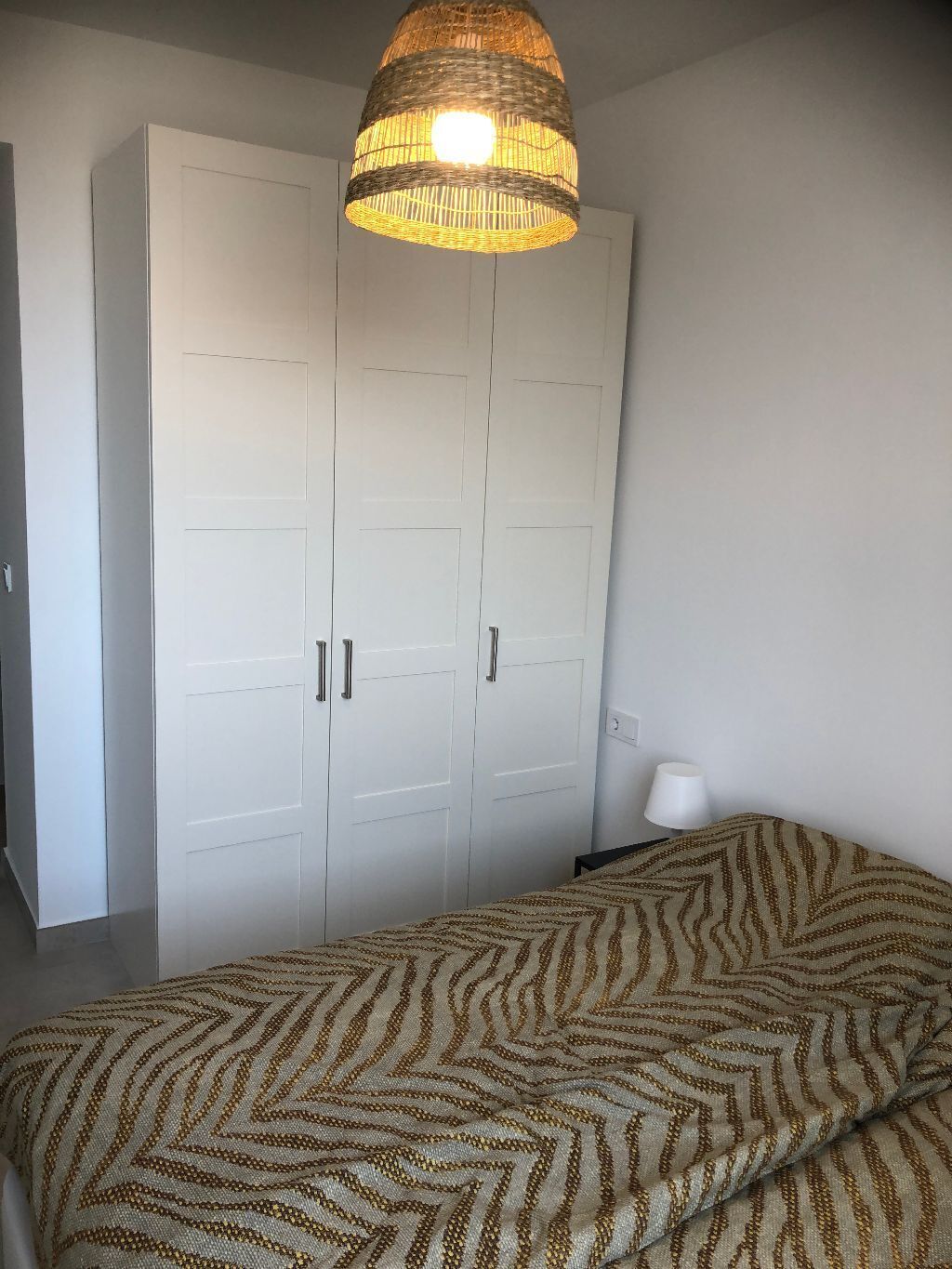 Un dormitorio con una cama, un armario y una lámpara colgante.