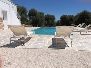 A poolside area with two lounge chairs and a stone-tiled deck.
