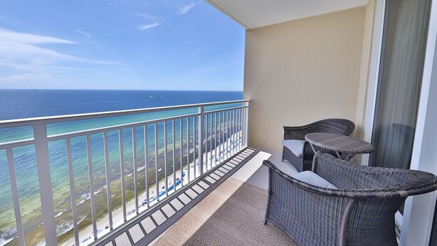 A balcony with wicker furniture and a view of the ocean.