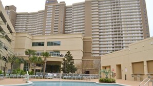 A hotel with a swimming pool, multiple floors, and balconies.