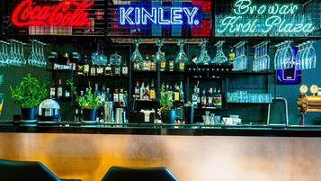 A bar with neon signs for Coca-Cola, Kinley, and Browar Kral Plaza.