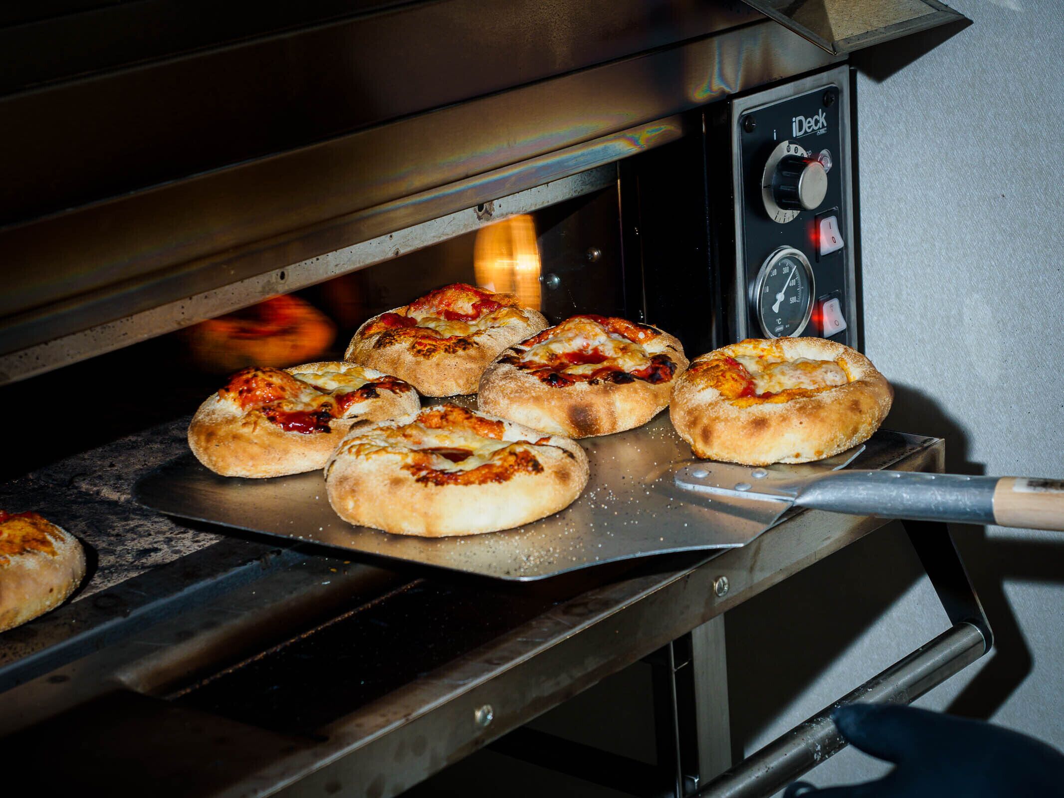 A pizza oven with several pizzas being baked inside.