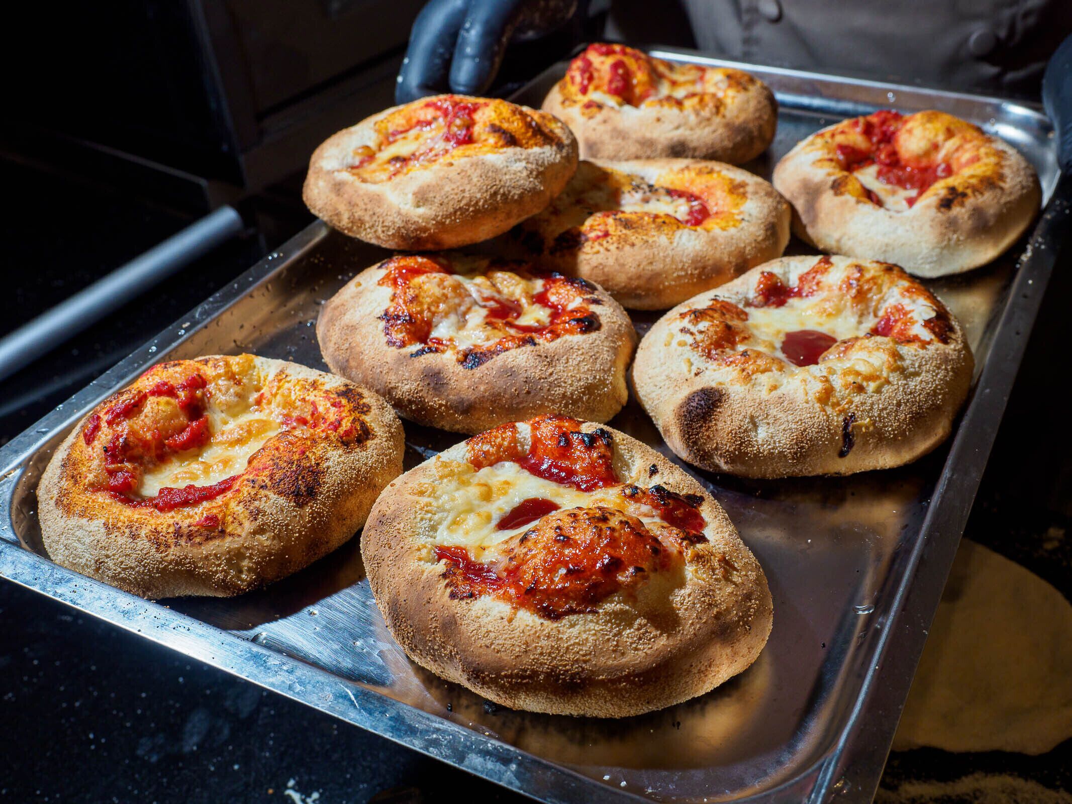 Eine Tablett mit frisch gebackenen Pizzen, mit goldbrauner Kruste, überzogen mit geschmolzenem Käse und Tomatensauce.
