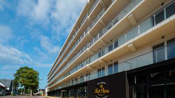 Un hotel moderno con varios pisos, ventanas amplias y un cartel llamativo que anuncia 'Sea Resort' y 'Royal Plaza Spa Wellness'.