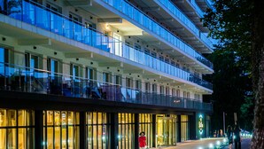 A modern hotel with a glass facade, multiple floors, and a well-lit entrance. - Resort Król Plaza Spa & Wellness (Postomino)