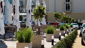 An outdoor seating area with umbrellas, chairs, and potted plants. - Resort Król Plaza Spa & Wellness (Postomino)