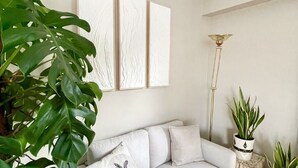A living room with a light-colored sofa, a large potted plant, and a floor lamp. - L'Artistik - Appt avec Balcon et parking (Vannes)