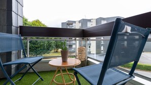 A balcony with two blue chairs, a small round table, and a potted plant. - L'Artistik - Appt avec Balcon et parking (Vannes)