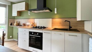 A modern kitchen with white cabinetry, a black range hood, and a wooden countertop. - L'Artistik - Appt avec Balcon et parking (Vannes)