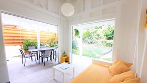 Une pièce lumineuse comprenant un lit, une petite table et une fenêtre donnant sur un jardin.