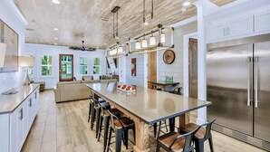 Una cocina amplia con una isla grande, electrodomésticos modernos y techo de madera.