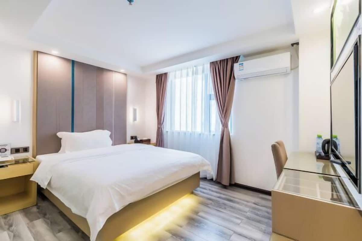 A hotel room with a bed, bedside table, and a desk with a chair.