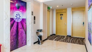 A hotel lobby with a marble floor, a reception desk, and a door with a sign.