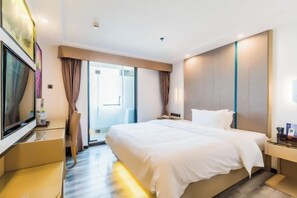 A hotel room with a bed, a TV, a desk, and a door leading to a balcony. - Wuchuan Cafeir Hotel (Wuchuan)