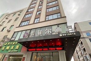 A hotel with a modern facade, multiple floors, and a prominent signage. - Wuchuan Cafeir Hotel (Wuchuan)