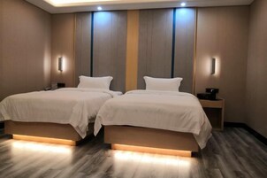 Una habitación de hotel con dos camas, una mesita de noche y una lámpara fijada a la pared.