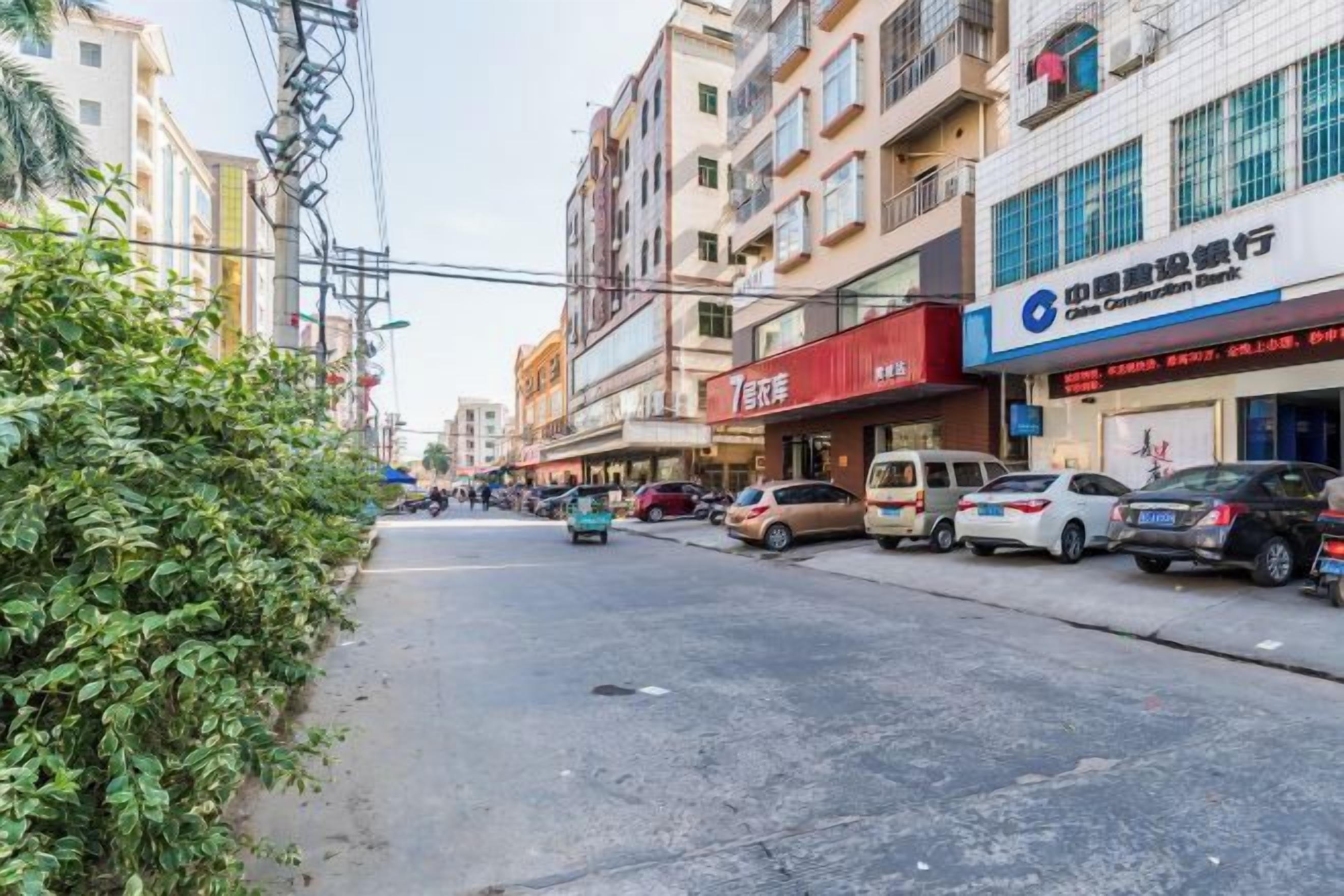 A street with buildings, parked cars, and a clear sky.
