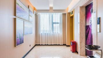 A hotel corridor with framed pictures on the walls, a red trash bin, and a door with a purple mural.