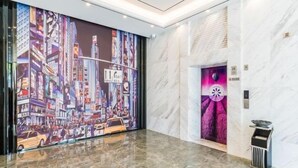 A lobby with a cityscape mural, marble walls, and a modern elevator.