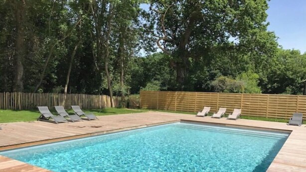 A rectangular swimming pool with clear blue water, surrounded by a wooden deck. - Petite Maison - Piscine & Vue mer Grange Ouest (Locoal-Mendon)