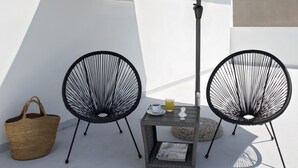 A rooftop terrace with two black wire chairs, a table with a newspaper, a basket, and a large black umbrella. - Hypnos Inn Athens (Athens)