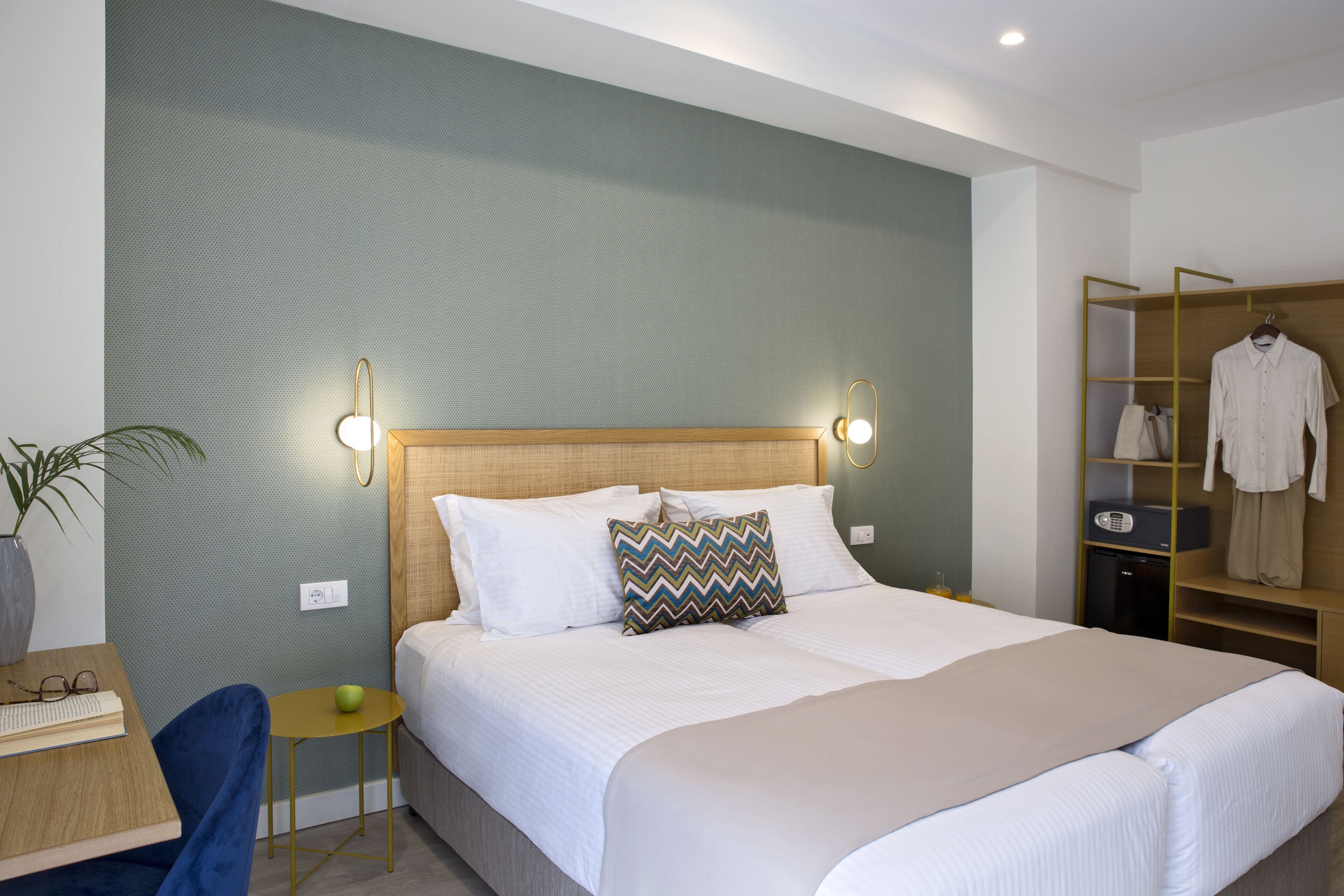 A modern hotel room with a large bed, bedside tables, a desk, and a wardrobe.