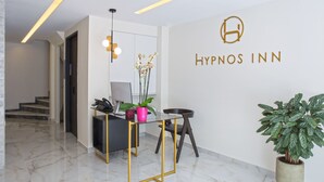 A reception area with a desk, chair, and potted plants. The wall has a logo and the name 'Hypnos Inn'. - Hypnos Inn Athens (Athens)
