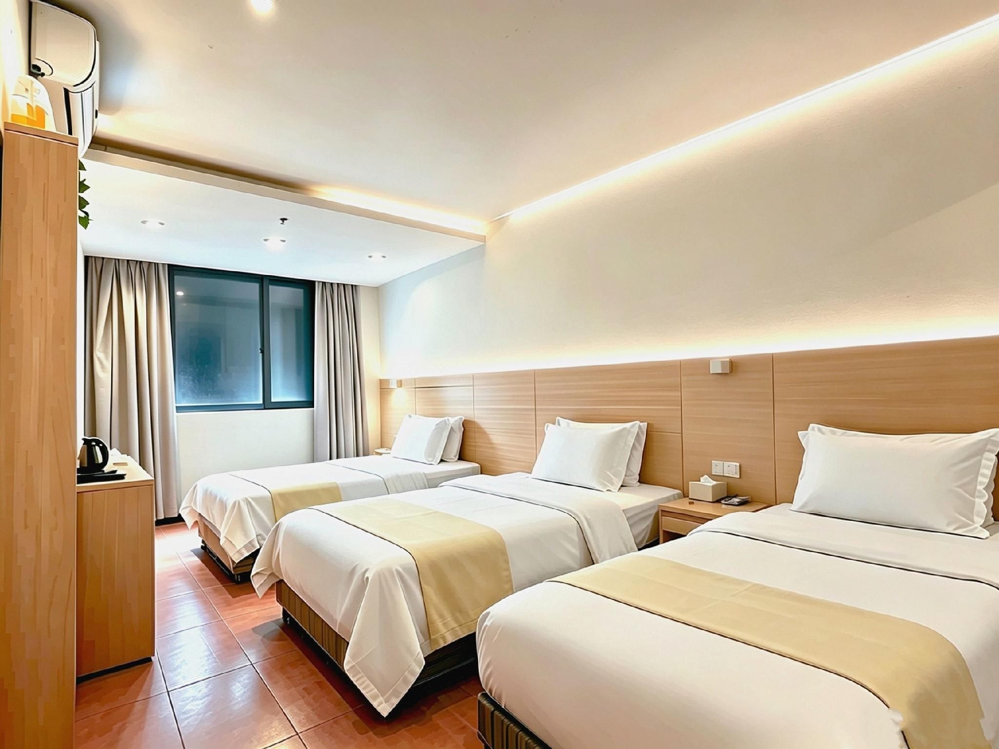 A hotel room with two beds, a bedside table with a lamp, a window with curtains, and a wooden wardrobe.
