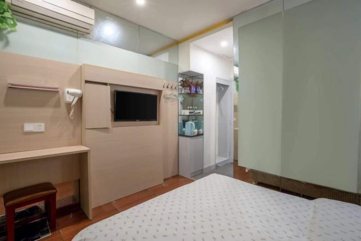 Un dormitorio con cama, televisor, una mesita y un armario.